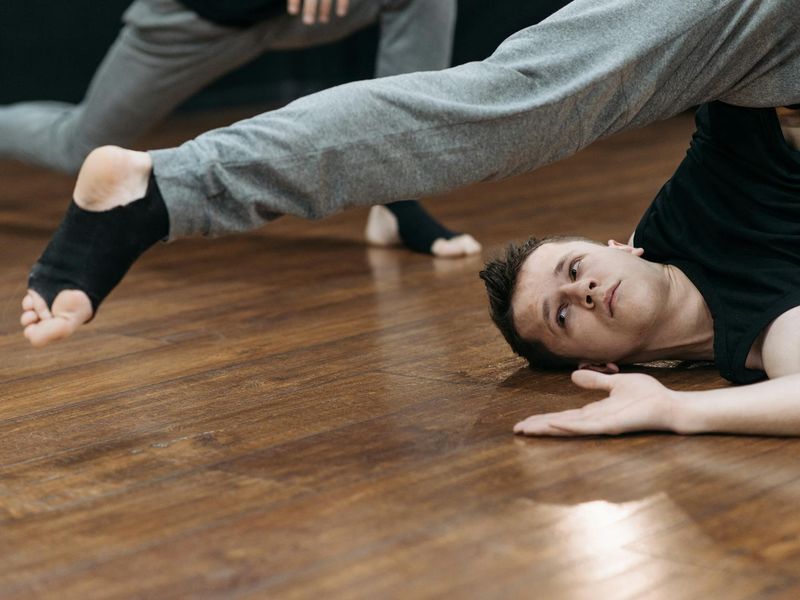 Person practicing slow controlled movements in a dark studio